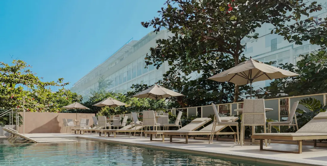 Piscina com espreguiçadeiras e guarda-sóis no rooftop do 6º pavimento do Soul Rio Gago Coutinho